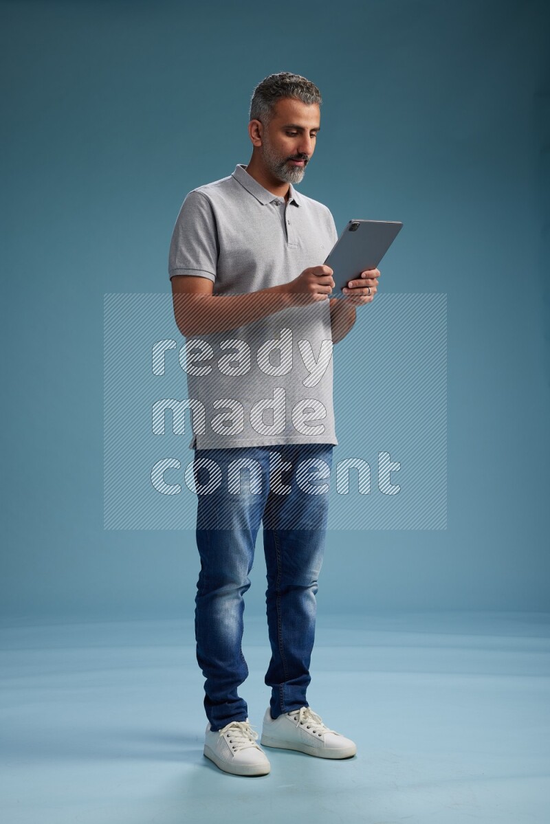 Man Standing working on tablet on blue background