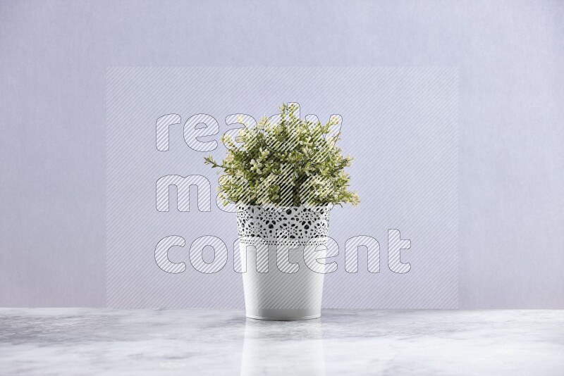 Artificial plant in white decorative pot on grey marble background
