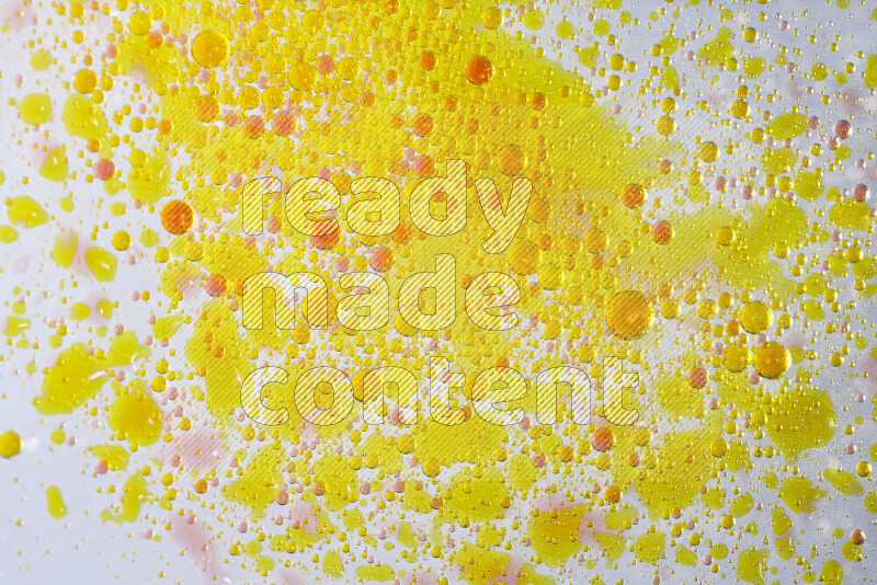 Close-ups of abstract yellow and red watercolor drops on oil Surface on white background