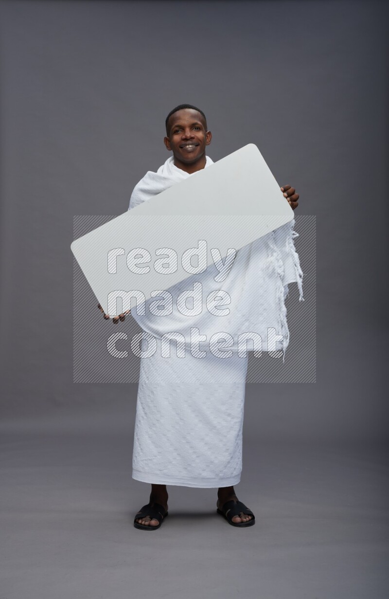 A man wearing Ehram Standing holding board sign on gray background