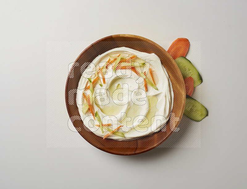 Lebnah garnished with sliced carrots & cucumber in a wooden plate on a white background
