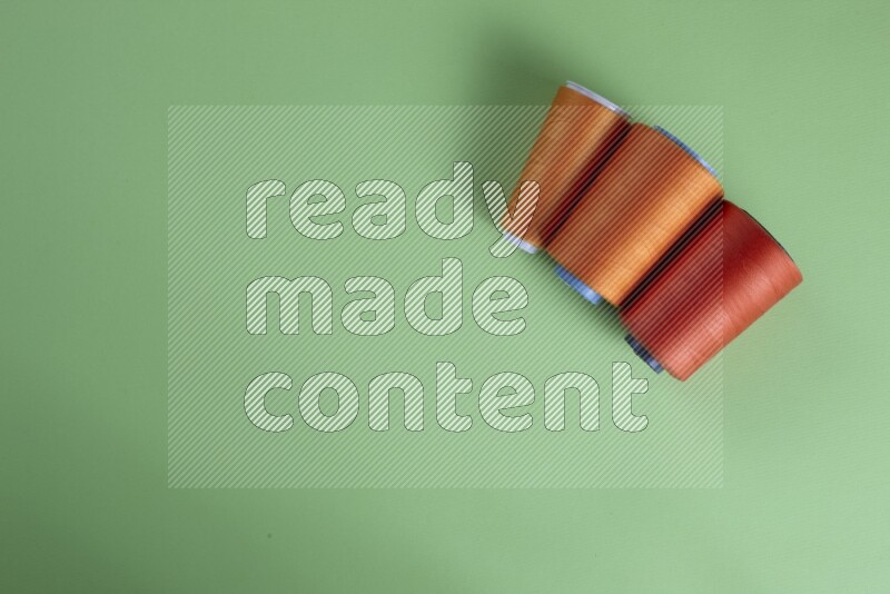 مجموعة من أدوات الخياطة والتفصيل برتقالية اللون على خلفية خضراء