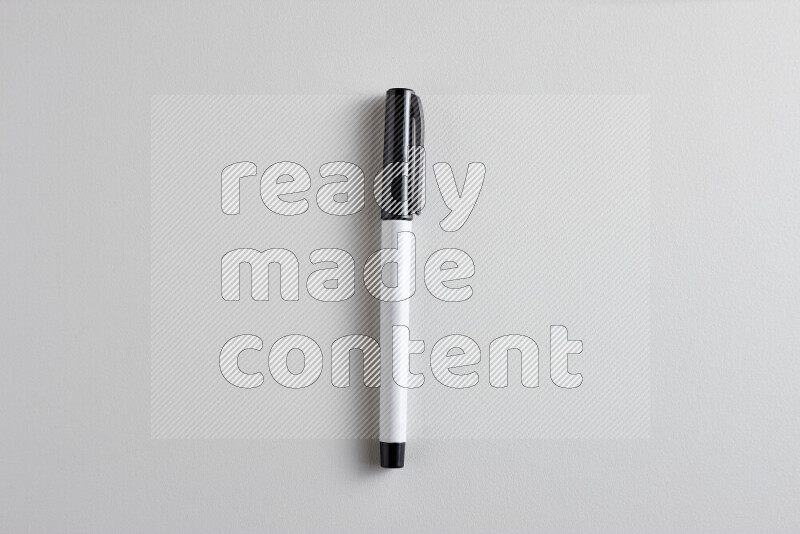 A close-up showing a single coloring pen with a cap on grey background