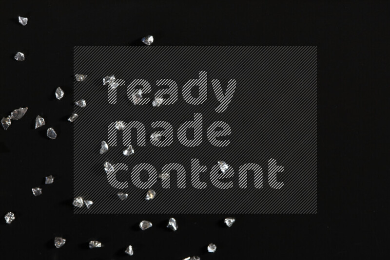 قطع زجاجية فضية لامعة متناثرة على خلفية سوداء