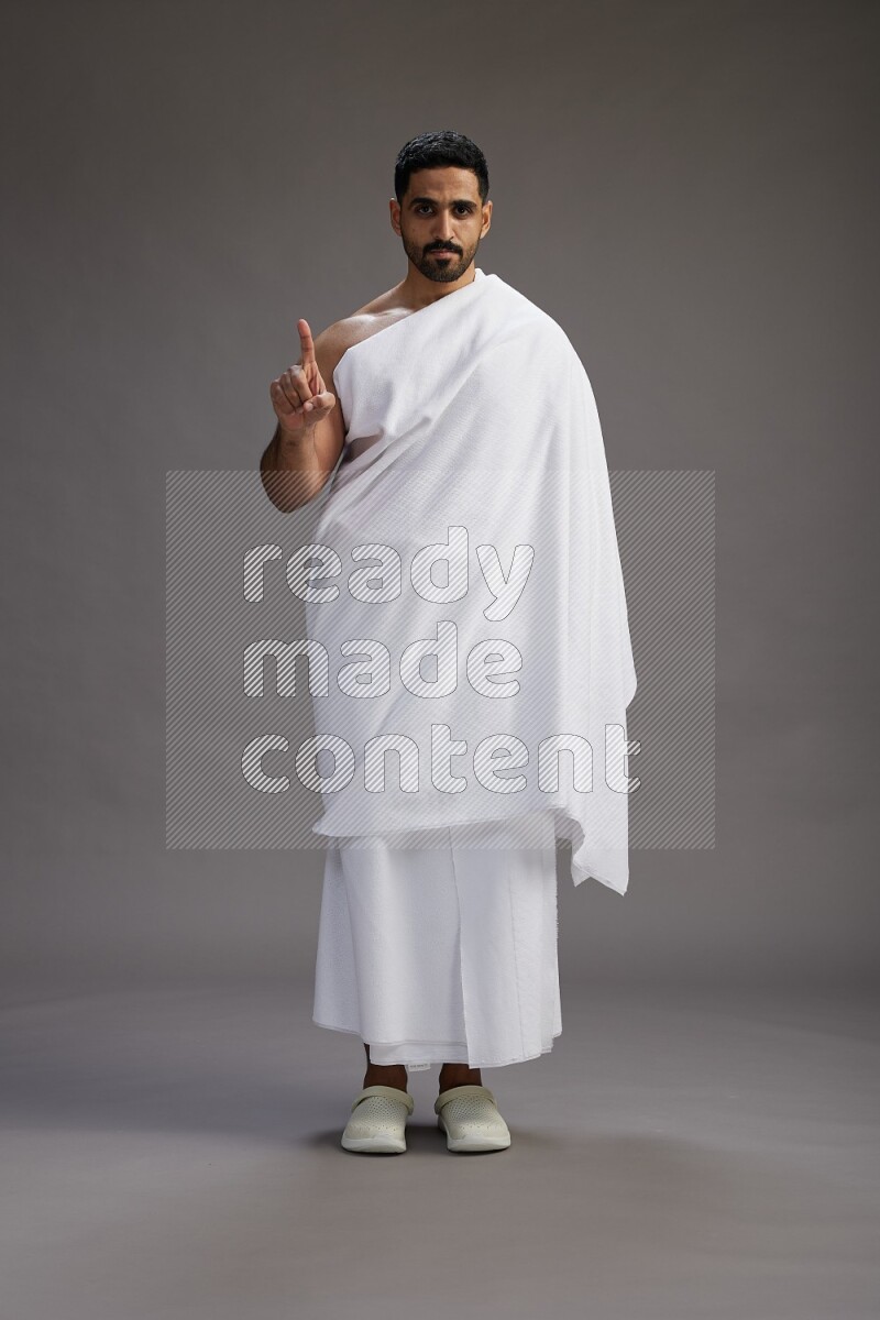 A man wearing Ehram Standing Interacting with the camera on gray background