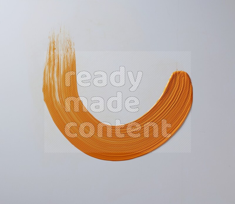 An orange half circular painting brush stroke on white background