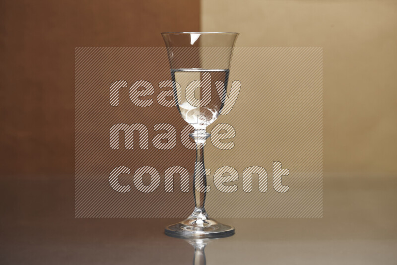 The image features a clear glassware filled with water, set against brown and beige background