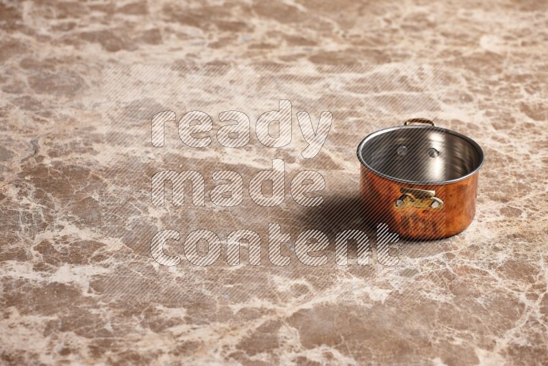 A small copper pot on beige marble background