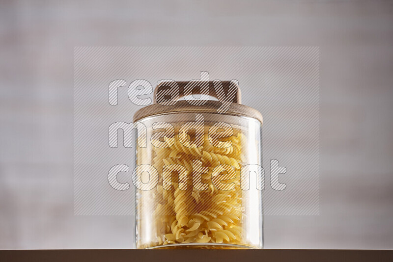 Raw pasta in glass jars on beige background