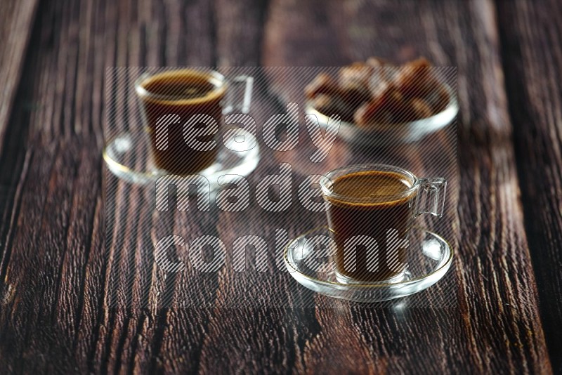 كوب زجاجي من القهوة مع التمر والشاي على خلفية خشبية