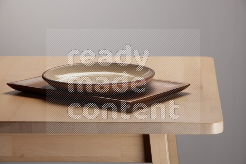 multicolored plate on a rectangular wooden tray on the edge of wooden table