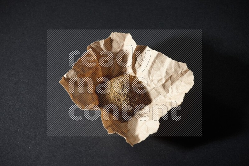 بودرة الكمون في قطعة من الورق على خلفية سوداء