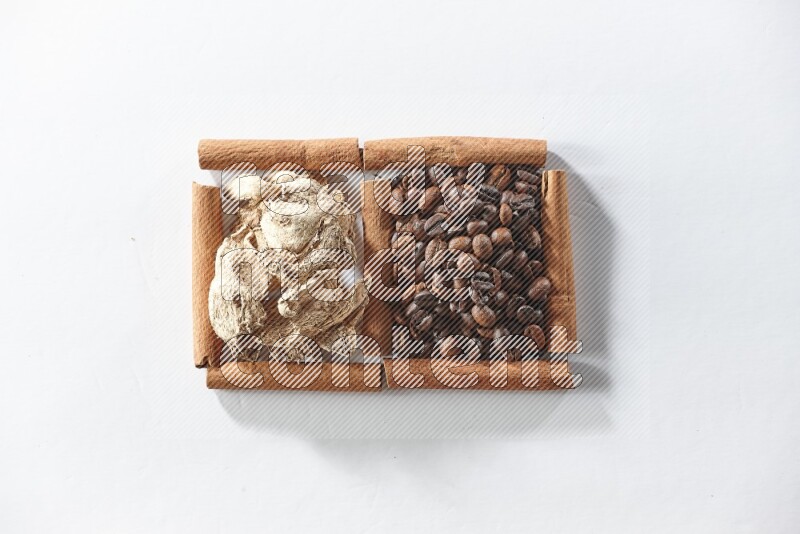 مربعان من أعواد القرفة ممتلئان بحبوب القهوة والزنجبيل المجفف علي خلفية بيضاء