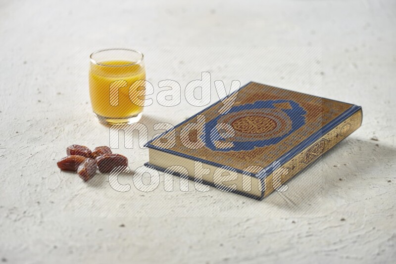 Quran with dates, prayer beads and different drinks all placed on textured white background