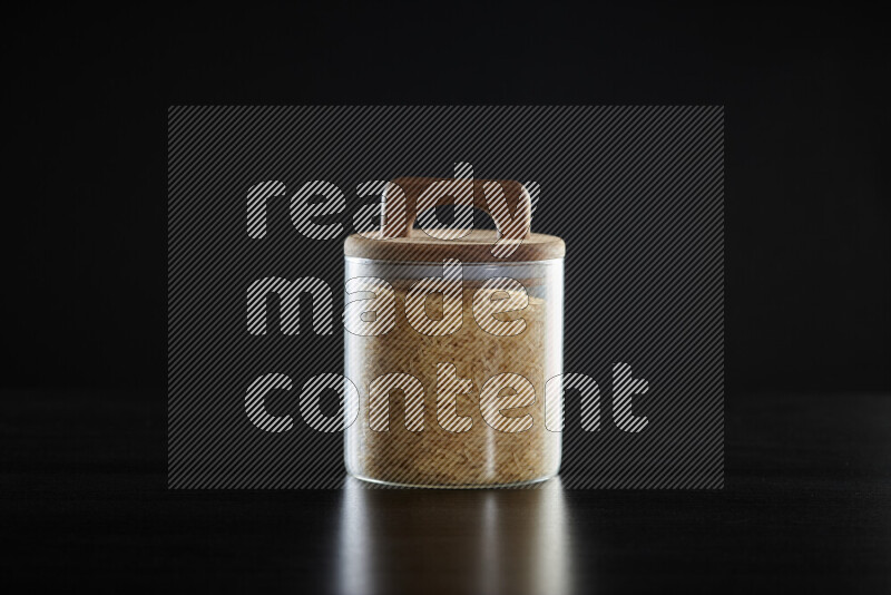 Basmati golden rice in a glass jar on black background