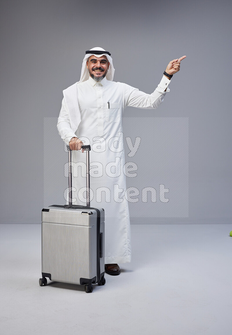 رجل سعودي يرتدي ثوب وشماغ بجانبه حقيبة سفر