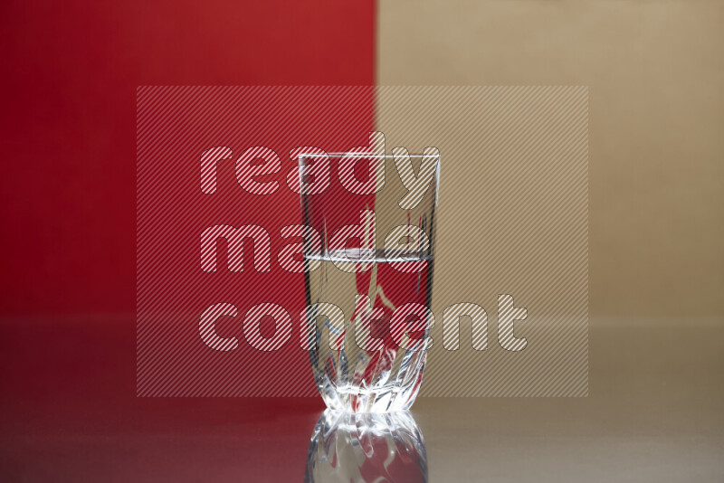 The image features a clear glassware filled with water, set against red and beige background