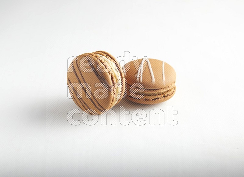 45º Shot of of two assorted Brown Irish Cream, and light brown  Almond Cream macarons on white background