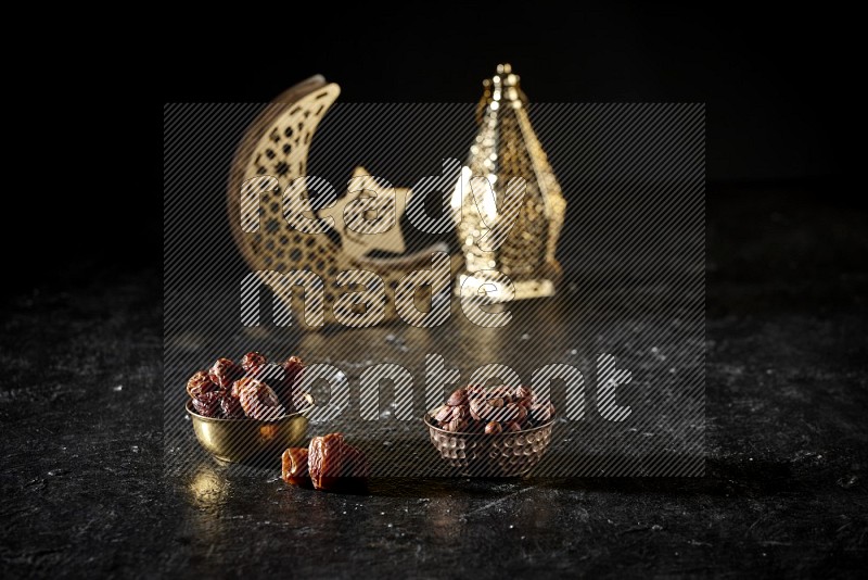 Dates in a metal bowl with hazelnuts beside golden lanterns in a dark setup