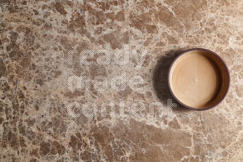 Top View Shot Of A Beige Pottery Oven Plate On beige Marble Flooring