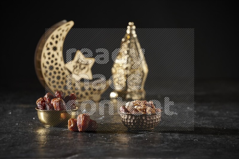 Dates in a metal bowl with mixed nuts beside golden lanterns in a dark setup