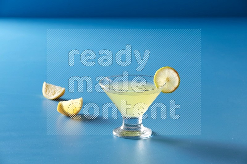 glass of lemon juice with lemon slice  on blue background