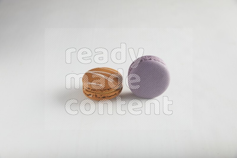 45º Shot of of two assorted Brown Irish Cream, and Purple Blueberry macarons on white background
