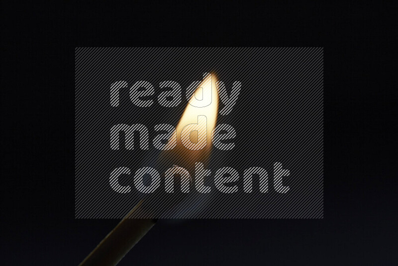 A burning matchstick isolated on dark backdrop