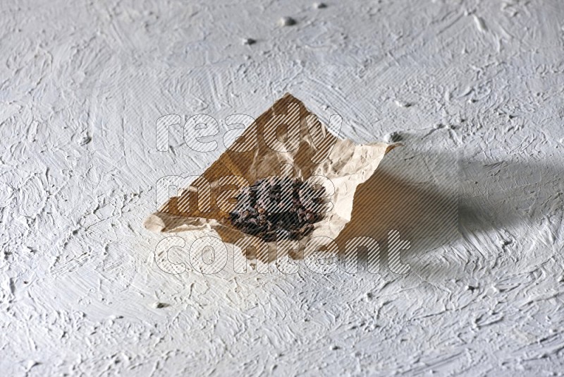 Cloves on crumpled piece of paper on a textured white flooring