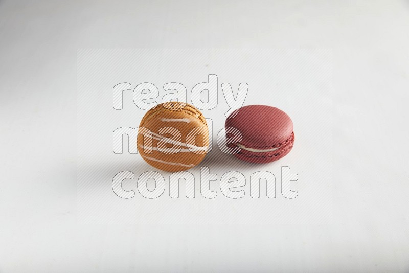 45º Shot of of two assorted Brown Irish Cream, and Red Velvet macarons on white background