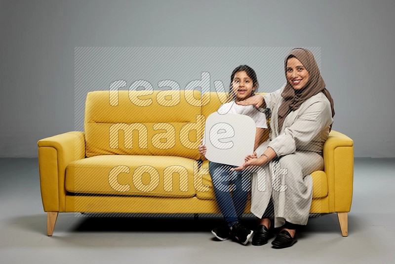 Mom and daughter sitting holding social media sign on gray background