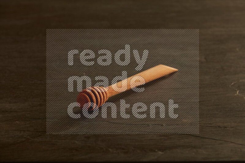 Wooden honey dipper on black slate background