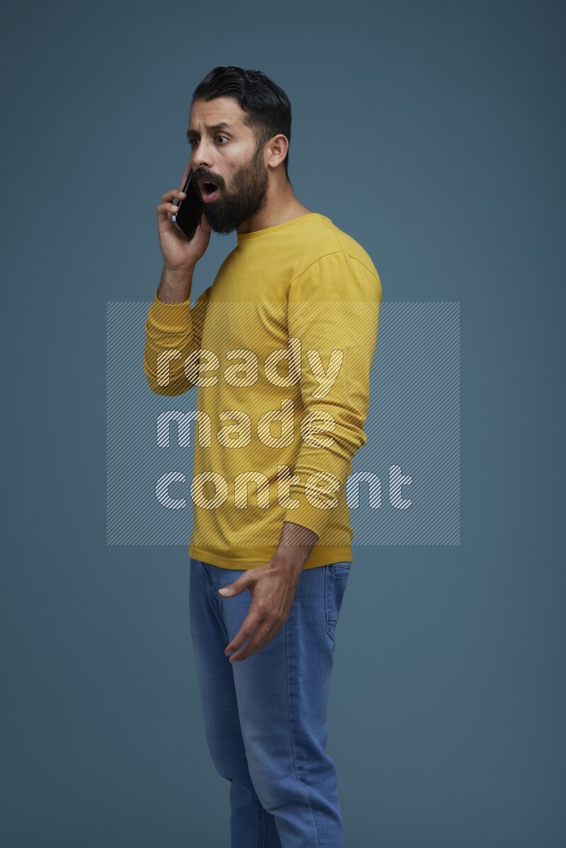 A man having a calling in a blue background wearing a yellow shirt