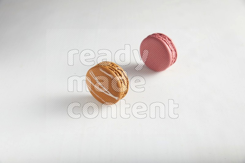 45º Shot of of two assorted Brown Irish Cream, and Pink Raspberry macarons on white background