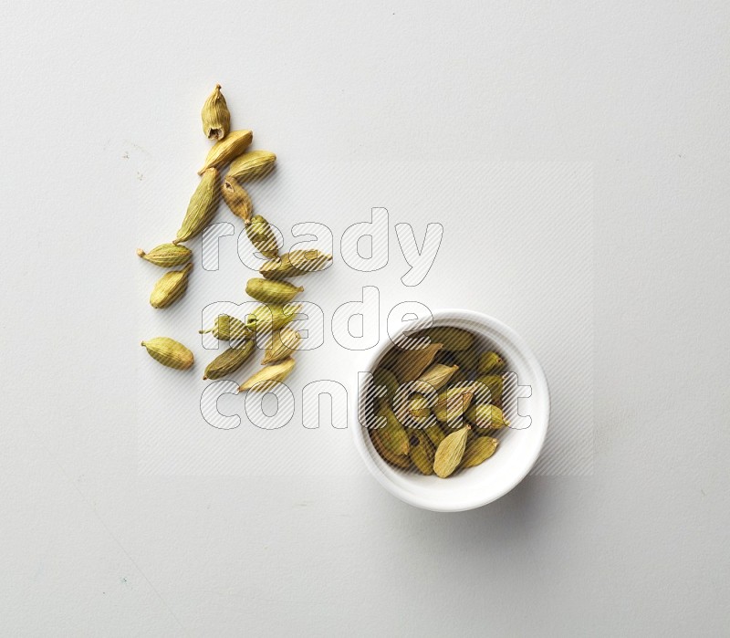 Top-view shot of Cardamon in a container on white background