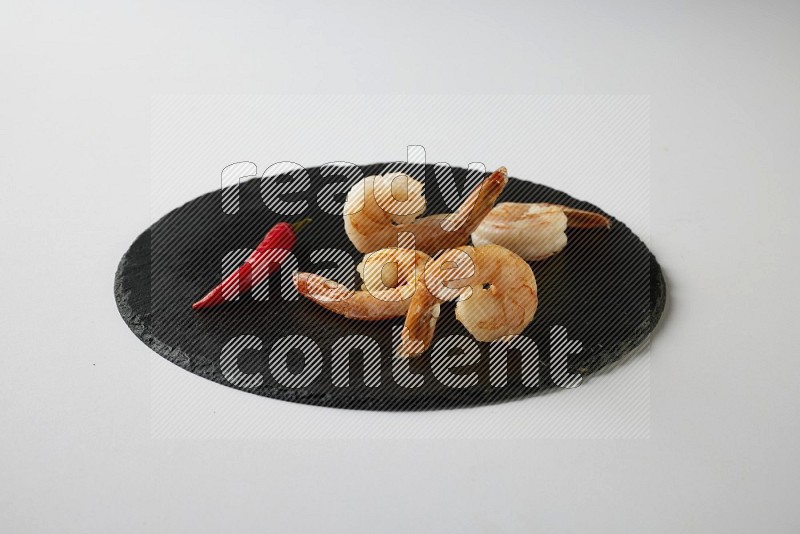 four grilled shrimp  on a black slate direct  on a white back ground