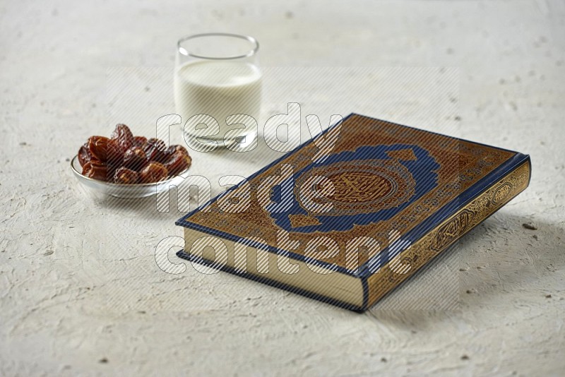 Quran with dates, prayer beads and different drinks all placed on textured white background