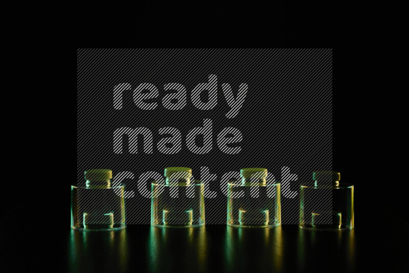 Glassware with rim light in green and yellow against black background