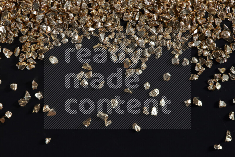 Gold shimmering fragments of glass scattered on a black background