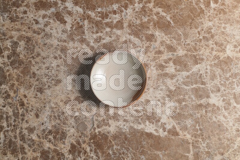 A multicolored pottery bowl on beige marble background