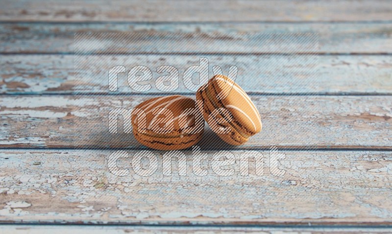45º Shot of two Brown Irish Cream macarons on a  light blue wooden background