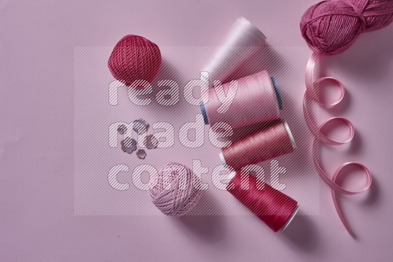 A pink collection of sewing and tailoring tools arranged on a pink background