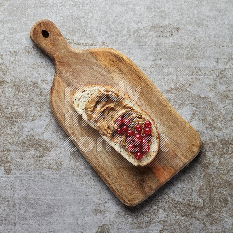 open faced peanut butter sandwich with cranberries and chia seeds grey textured background