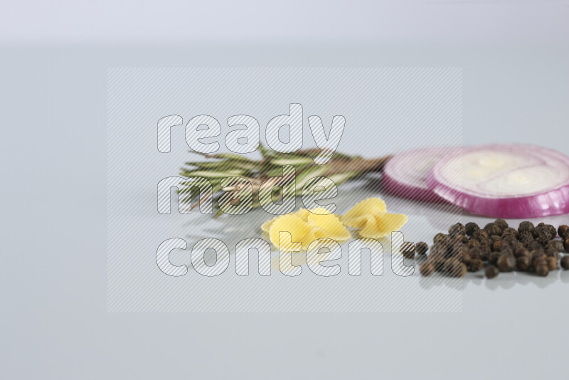 Raw pasta with different ingredients such as cherry tomatoes, garlic, onions, red chilis, black pepper, white pepper, bay laurel leaves, rosemary, cardamom and mushrooms on light blue background