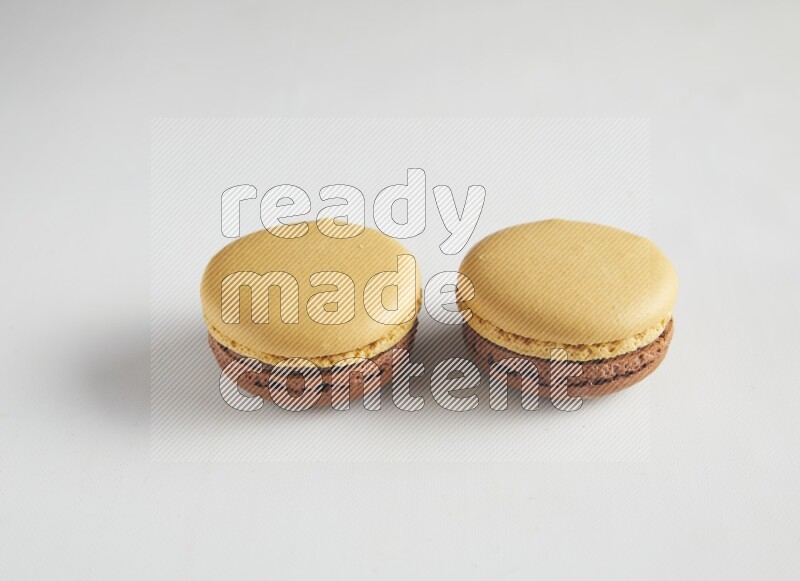 45º Shot of two Yellow and Brown Chai Latte macarons on white background