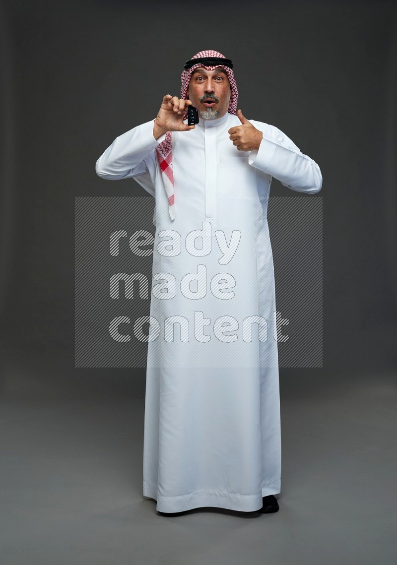 Saudi man with shomag Standing holding car key on gray background