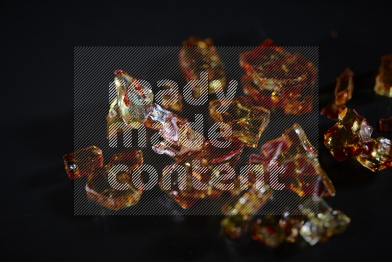 Transparent orange fragments of glass scattered on a black background