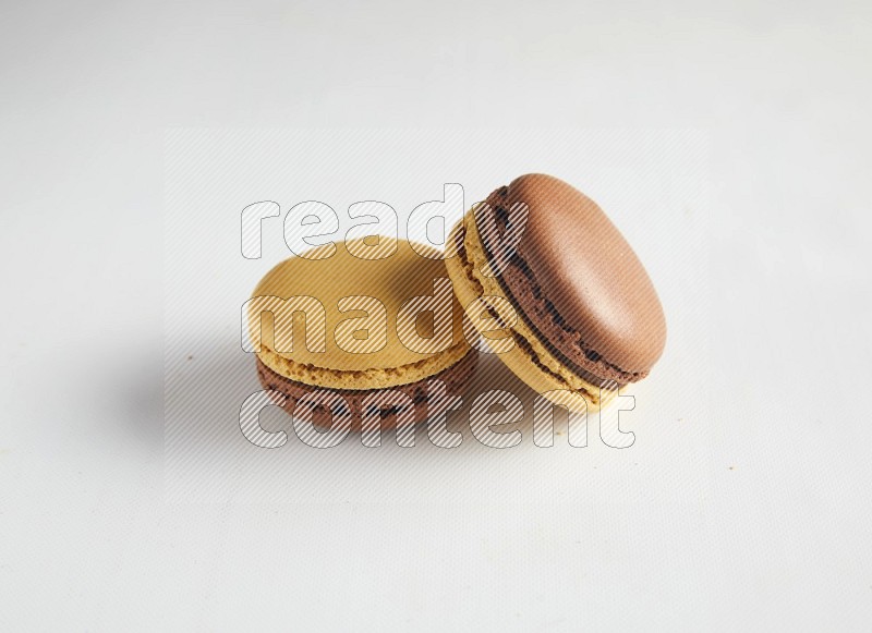 45º Shot of two Yellow and Brown Chai Latte macarons on white background