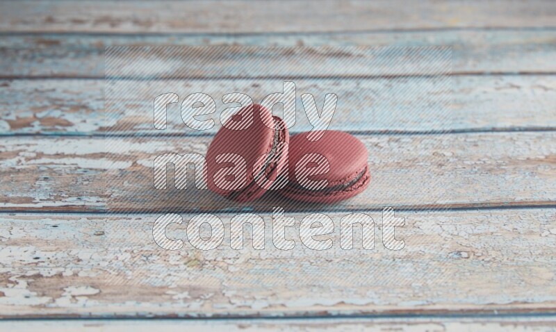 45º Shot of two Red Cherry macarons on light blue wooden background