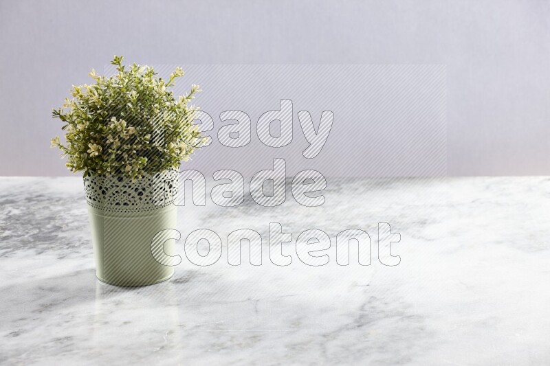 Artificial plant in green decorative pot on grey marble background